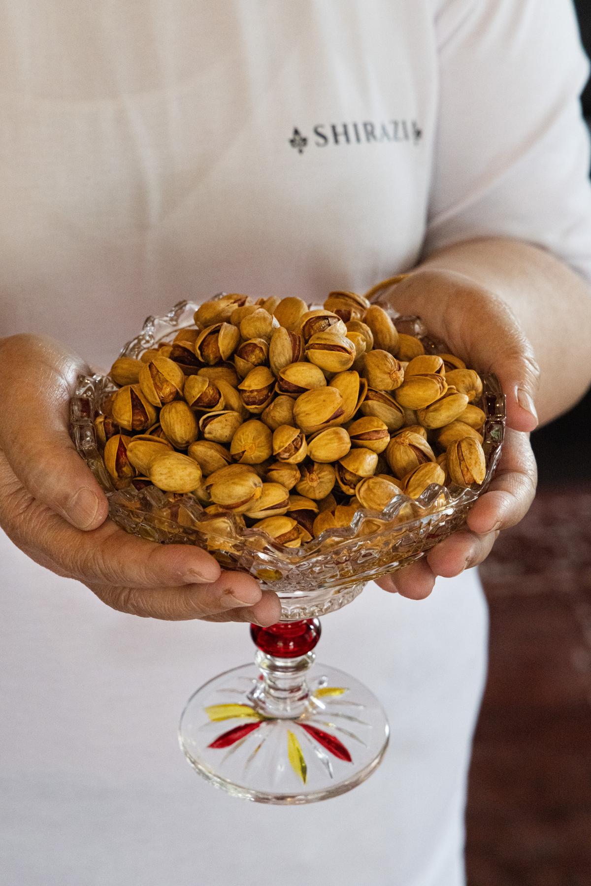 A bowl of golden pistachios, offered at the door