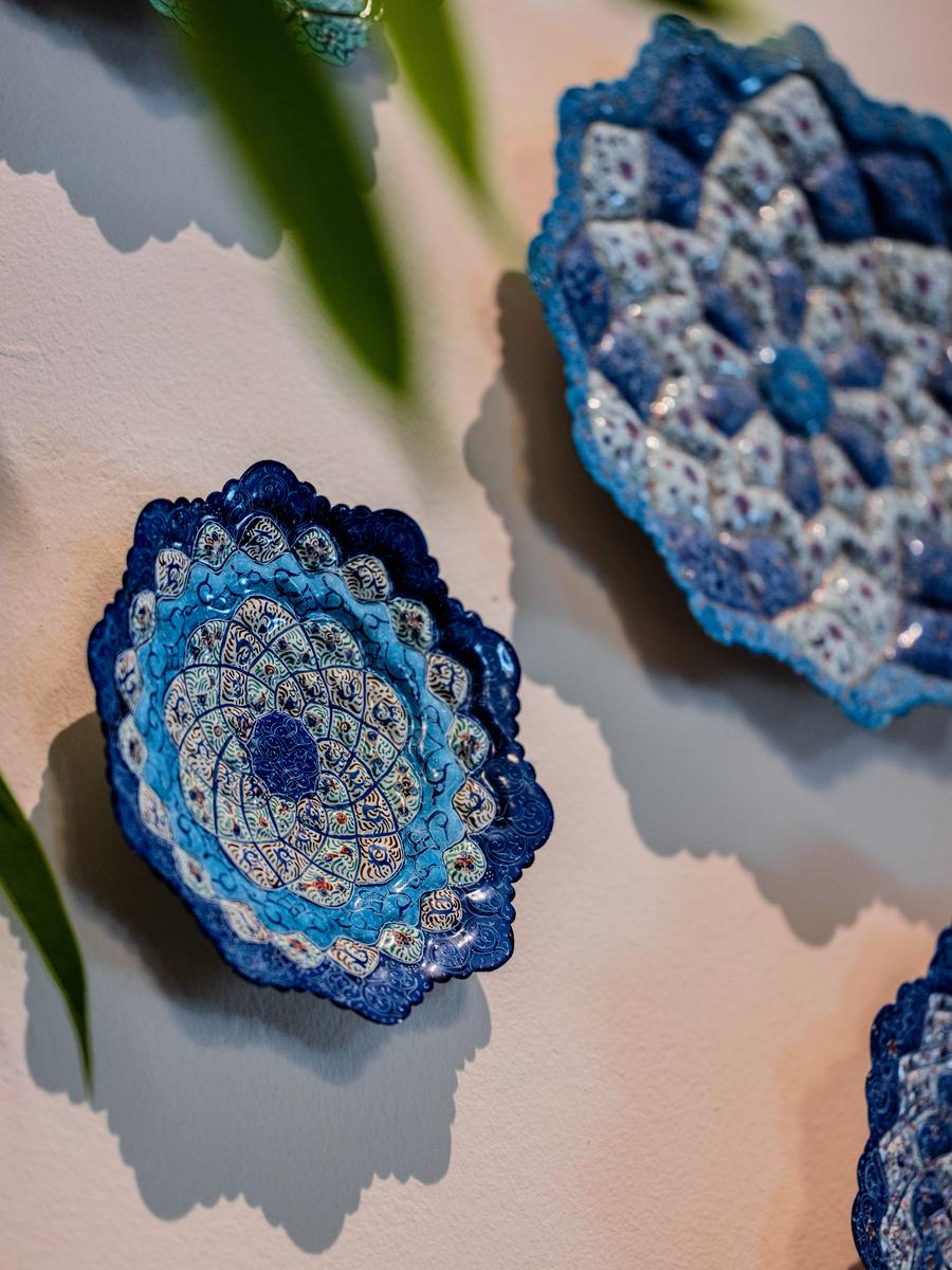 Blue minakari plates hung against the cream wall